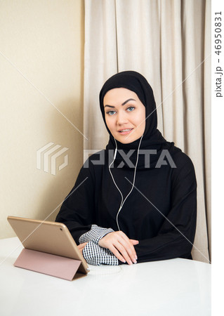 Arabic woman using tablet pc computer. Southeast Asian student at home. Muslim teenage girl living Arabic woman using tablet pc computer. Southeast Asian student at home. Muslim teenage girl living 46950831