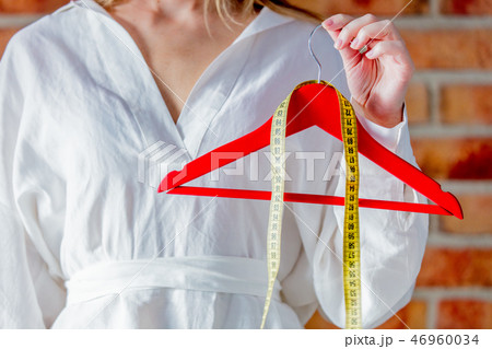 fashion designer hands with hanger and measure tape 46960034