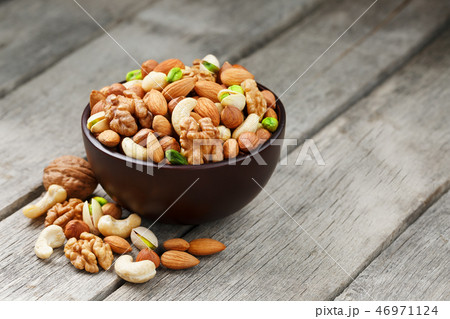 Wooden bowl with mixed nuts on a wooden gray Wooden bowl with mixed nuts on a wooden gray 46971124