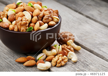 Wooden bowl with mixed nuts on a wooden gray  46971125