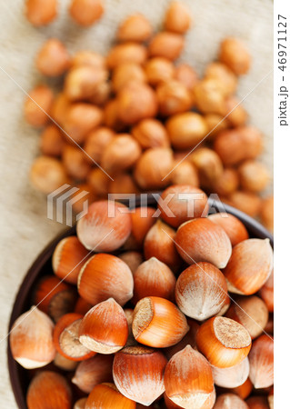 Peeled hazelnuts in a wooden, dark brown cup on  46971127