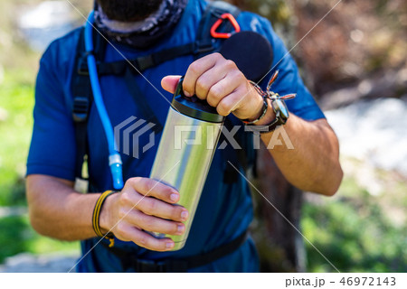 Hiker opening thermos on a hiking trip close up 46972143