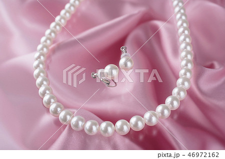 ピンク色背景の真珠のネックレスとイヤリングの写真素材 [46972162