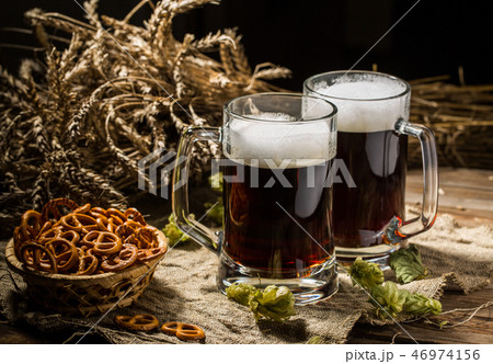 Two tankard beer with wheat and hops , basket of pretzels 46974156