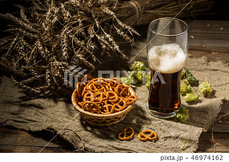 Glass beer with wheat and hops, basket of pretzels 46974162