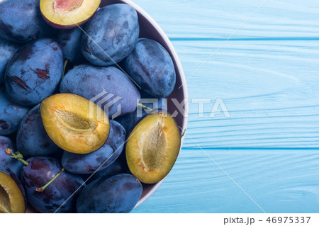Fresh plums in bowl on wooden table 46975337