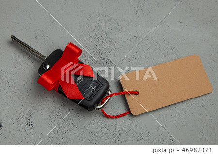 Gift Car keys with remote control alarm with red ribbon with bow and label tag. Gray background. 46982071