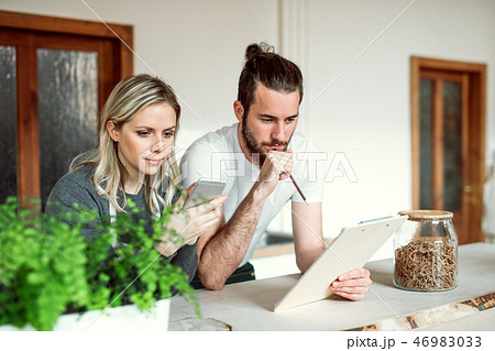 Two shop assistants standing at the counter in zero waste shop, checking stock. 46983033