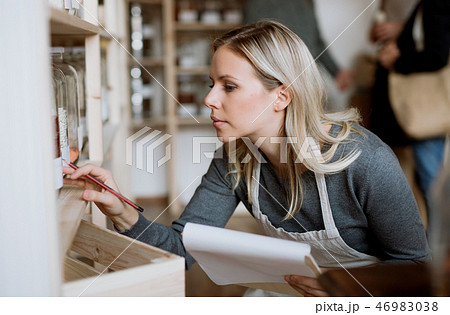 A female shop assistant working in a zero-waste shop. A female shop assistant working in a zero-waste shop. 46983038