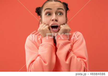Beautiful woman looking suprised isolated on coral Beautiful woman looking suprised isolated on coral 46984086