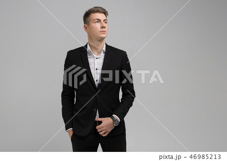 Portrait of young man with hands in pockets in black suit isolated on white background 46985213