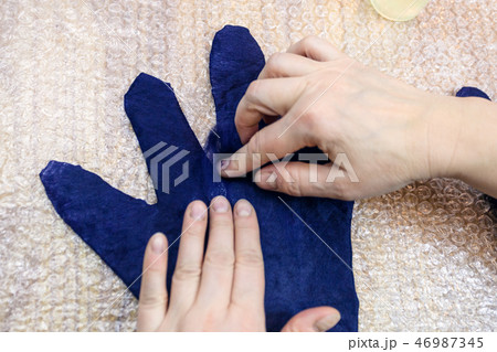 craftsman adds fibers on fingers of wet glove 46987345