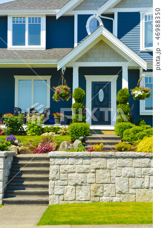 Entrance of luxury family house with landscaped front yard on land terrace Entrance of luxury family house with landscaped front yard on land terrace 46988350