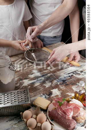Mom with children preparing the dough for pizza Mom with children preparing the dough for pizza 46988564