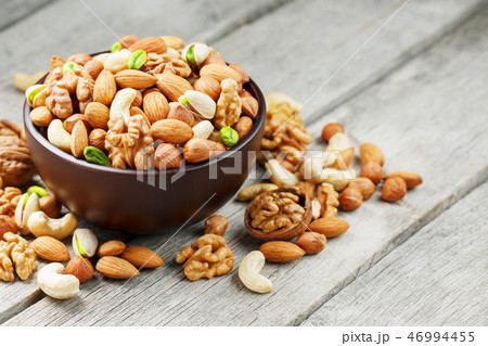 Wooden bowl with mixed nuts on a wooden gray Wooden bowl with mixed nuts on a wooden gray 46994455