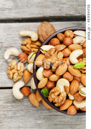 Wooden bowl with mixed nuts on a wooden gray  46994456