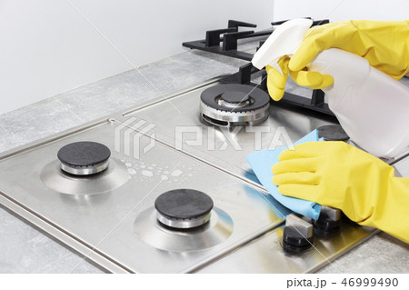 Cleaning a gas stove with kitchen utensils, household concepts, or hygiene and cleaning. 46999490