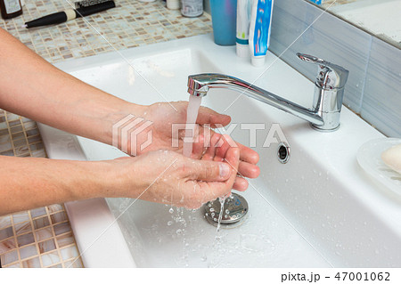 A man washes the wound under the tap 47001062