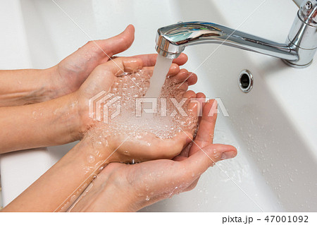 Children's and adult hands take water flowing from the mixer in the palm Children's and adult hands take water flowing from the mixer in the palm 47001092