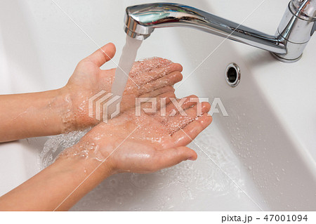 Children's hands under a strong stream of water from the mixer in the bathroom 47001094