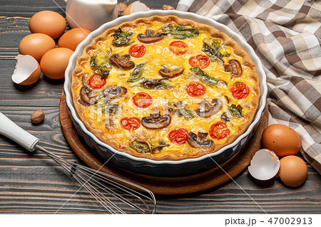 Baked homemade quiche pie in ceramic baking form, eggs and cream 47002913