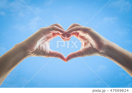 Heart shape woman hands against blue sky backgroun 47009624