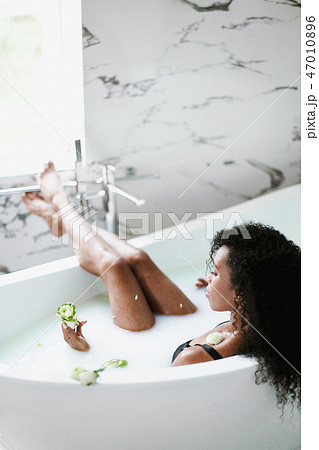 Young black girl lying in bathroom with marble tile and relaxing. Young black girl lying in bathroom with marble tile and relaxing. 47010896