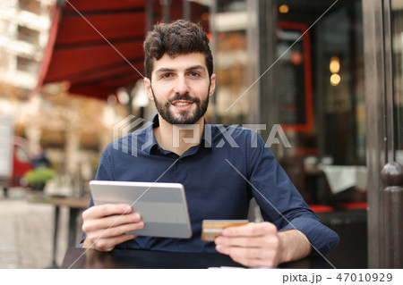 Young father buying online with card by smartphone at cafe in . Young father buying online with card by smartphone at cafe in . 47010929