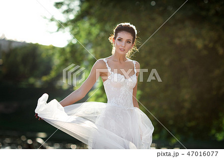fashion photo of beautiful woman with dark hair in luxurious wedding dress posing outdoor. fashion photo of beautiful woman with dark hair in luxurious wedding dress posing outdoor. 47016077