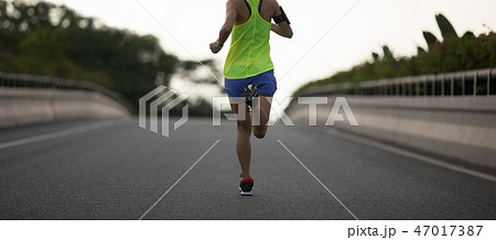 Young woman runner running on city road 47017387
