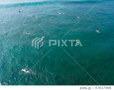 Aerial view of surfers paddling for catching waves Aerial view of surfers paddling for catching waves 47017406