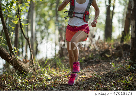 Sportswoman cross country trail running in forest 47018273