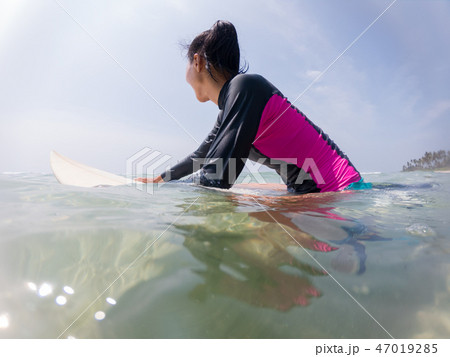 woman in swimming suit resting on surfing board woman in swimming suit resting on surfing board 47019285