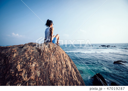 sit on seaside cliff edge looking at the distance 47019287