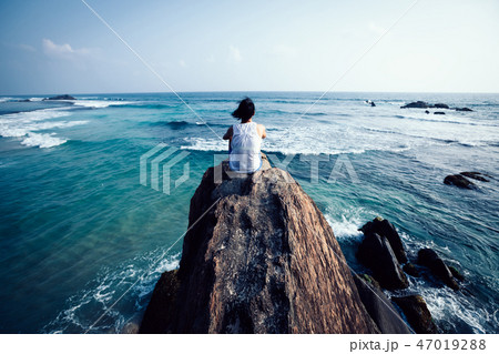 sit on seaside cliff edge looking at the distance 47019288