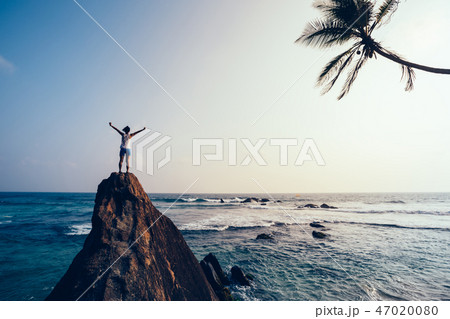 young woman  open arms on seaside rock cliff edge 47020080