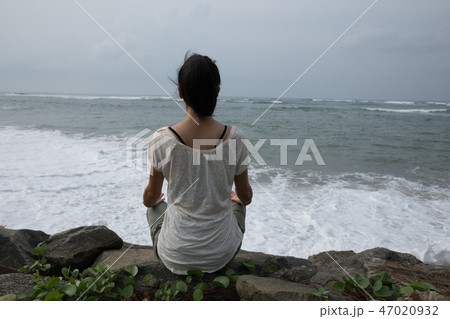 woman sit at the seaside on the rock meditation 47020932