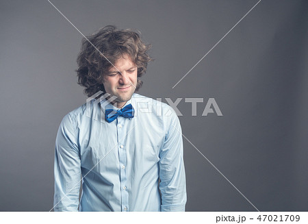 Portrait of exhausted sad guy with shaggy hair standing and looking down with apathy. Isolated on Portrait of exhausted sad guy with shaggy hair standing and looking down with apathy. Isolated on 47021709