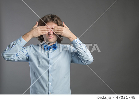 Man covering his eyes with hands on gray background. Shy male closing eyes by hands can't see hiding 47021749