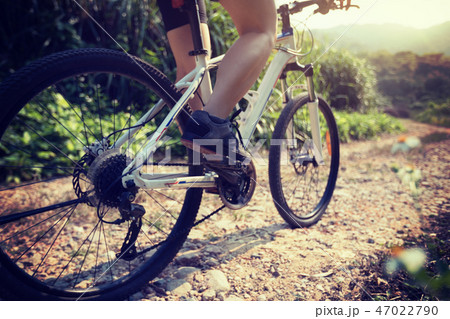 Woman cyclist riding mountain bike on rocky trail Woman cyclist riding mountain bike on rocky trail 47022790