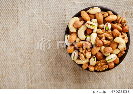 Mix of different nuts in a wooden cup against the  47022858
