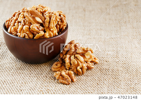 Peeled walnuts in a wooden, dark brown cup Peeled walnuts in a wooden, dark brown cup 47023148