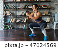 Woman doing squat workout and smiling during fitness training at home 47024569