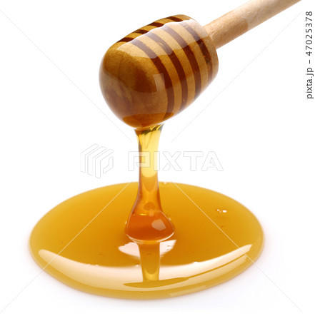 Honey dripping from dipper on white background 47025378