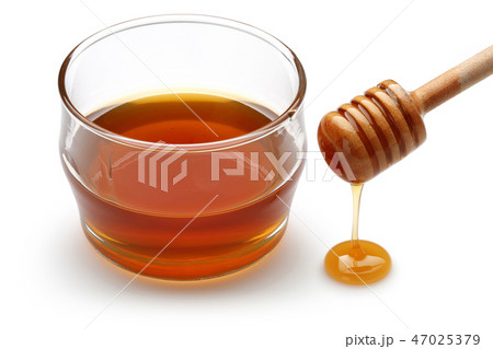 Honey dripping from dipper and honey in bowl 47025379