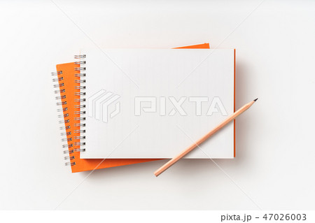 Top view of orange spiral notebook, page, pencil 47026003
