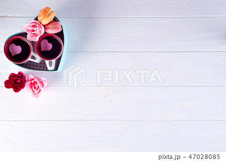 two cups of coffee, macaroons with flowers in a box in the form of a heart on a white background 47028085