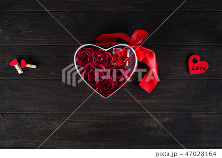 Valentines background with red hearts shaped and bouquet rose in gift box on dark wooden background Valentines background with red hearts shaped and bouquet rose in gift box on dark wooden background 47028164