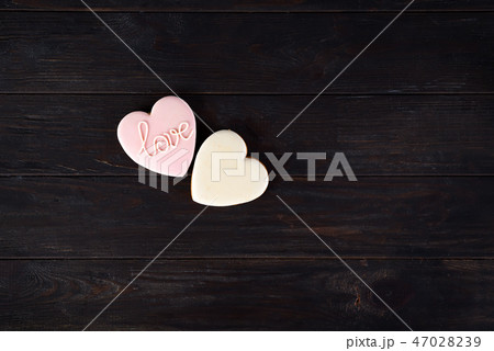 Sweets on Valentine's Day. Cookies in shape of heart and with lettering Love on dark wooden Sweets on Valentine's Day. Cookies in shape of heart and with lettering Love on dark wooden 47028239