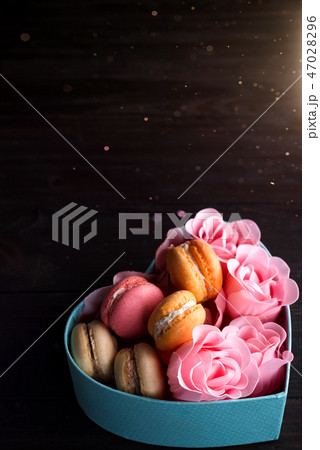 Macaroons in box. Festive round blue box with cookies and Rose on dark wooden background, copy space 47028296